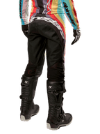 Alpinestars Stella 2024 Techstar dames motorcrossbroek, zwart multicolor, achteraanzicht met opvallende witte branding op het zitvlak, gedragen met zwarte Tech 3-laarzen en een bijpassende multicolor jersey, professionele off-road racekleding.