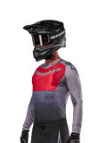 Alpinestars 2024 Supertech Dade jersey, motocross shirt, Iron Red Berry en grijs, lange mouwen met lasergesneden perforaties, gedragen door een rijder met zwarte helm en handschoenen, pro-level atletische racepasvorm