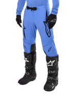 Alpinestars 2024 Supertech Dade broek, motorcrossbroek, lichtblauw met zwarte grafische logo's, voorzien van ventilatieperforaties en een magnetische taillesluiting, gecombineerd met zwarte technische rijlaarzen en handschoenen, professionele off-road race-uitrusting