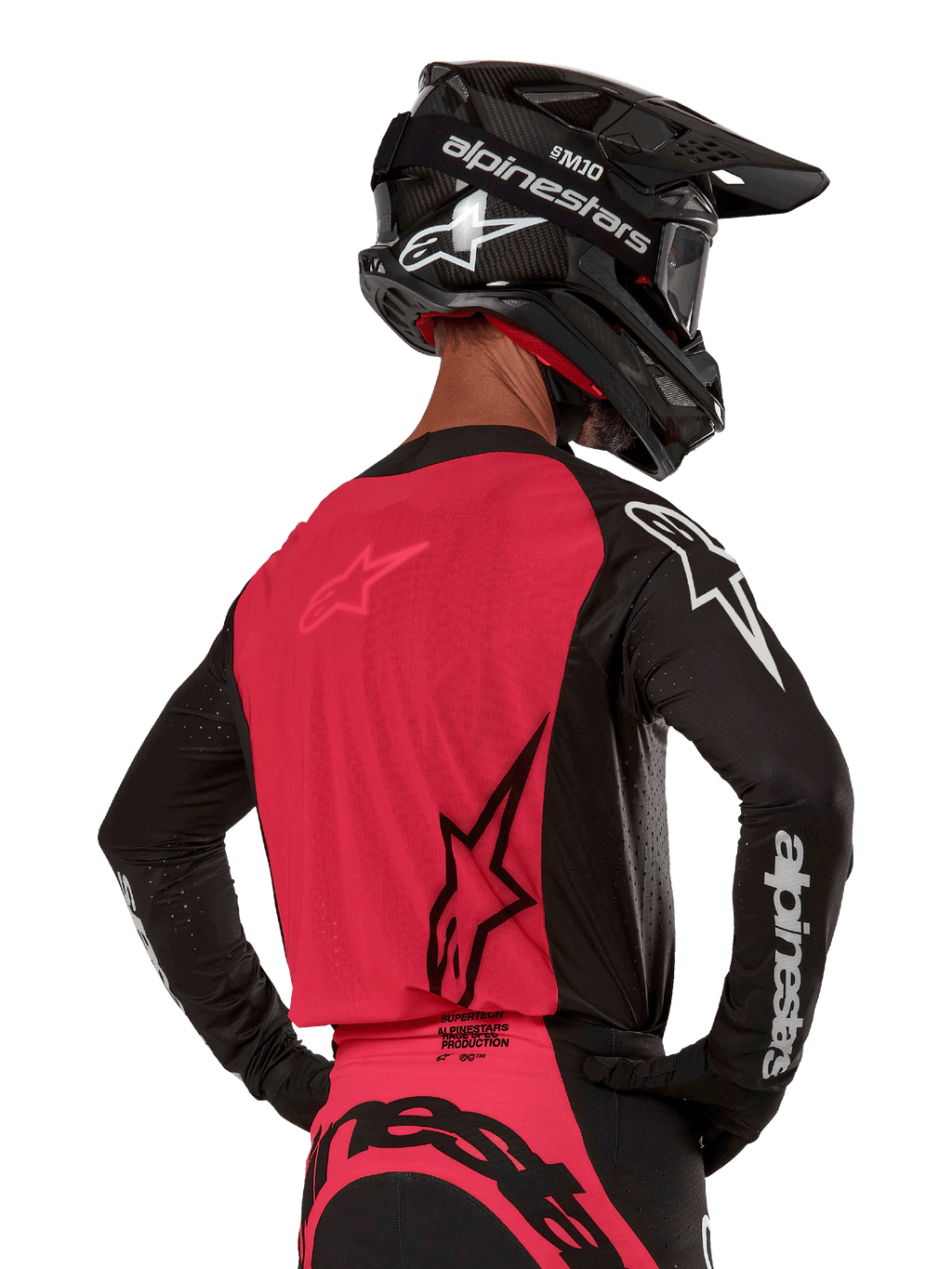 Alpinestars 2024 Supertech Ward Jersey, motorcross shirt, zwart en Red Berry, achterkant met rood mesh paneel en zwarte mouwen met witte logo's, gedragen met een zwarte carbon helm en handschoenen, atletische racepasvorm voor off-road rijden