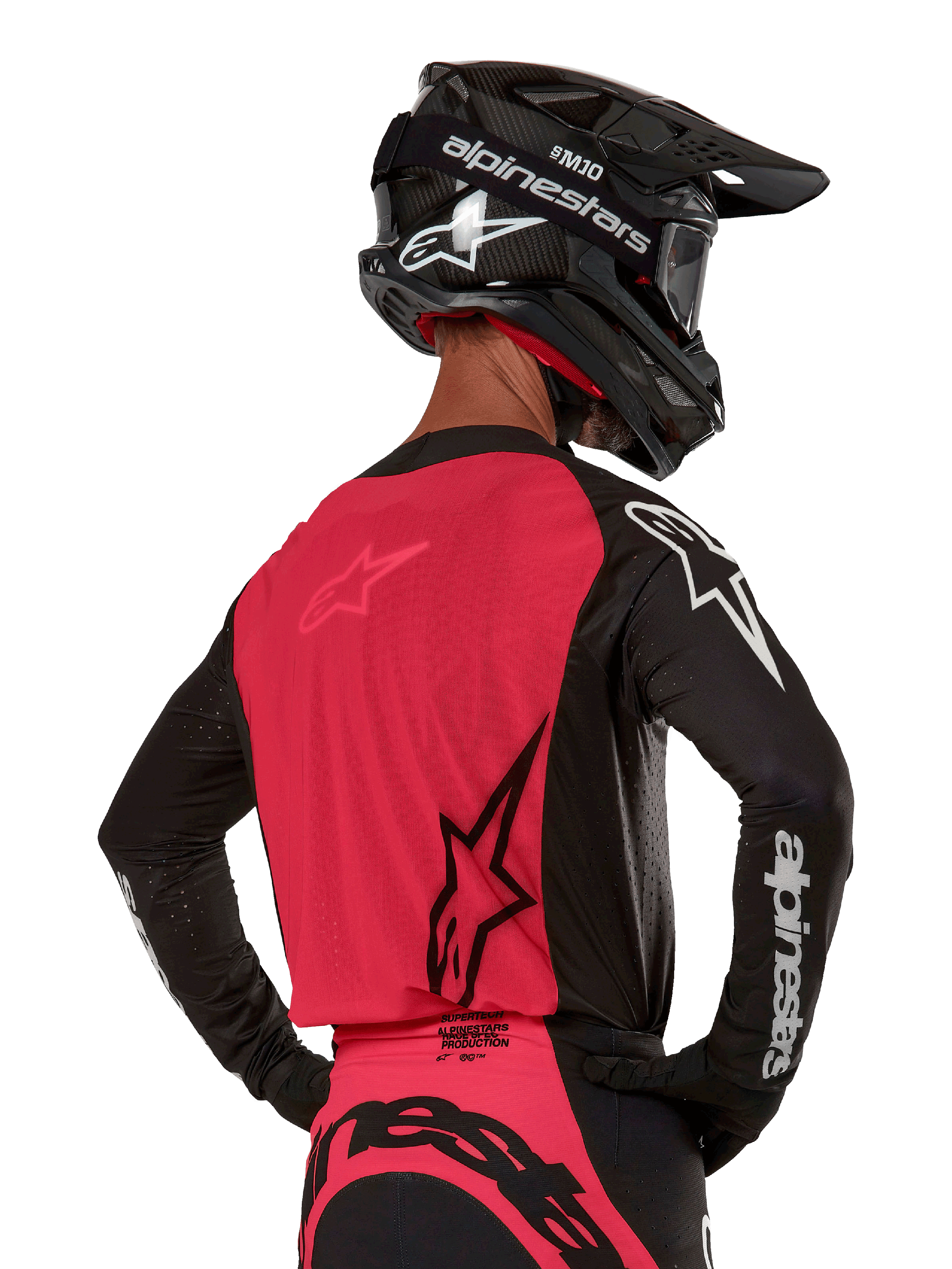 Alpinestars 2024 Supertech Ward Jersey, motorcross shirt, zwart en Red Berry, achterkant met rood mesh paneel en zwarte mouwen met witte logo's, gedragen met een zwarte carbon helm en handschoenen, atletische racepasvorm voor off-road rijden