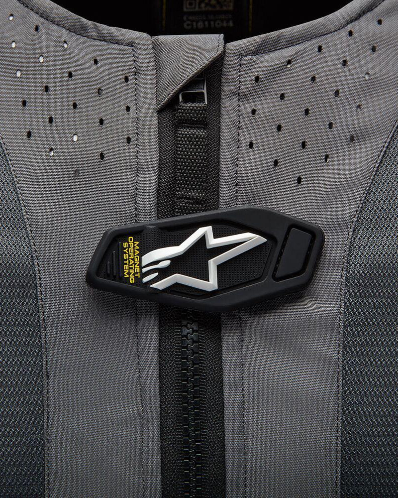 Alpinestars Tech-Air 5 Systeem detail, magnetische flap met wit sterlogo op grijze geperforeerde stof.