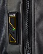 Tech-Air 5 led-display op een donkergrijs textiel vest met een oplichtend groen lampje en een grote zwarte rits.