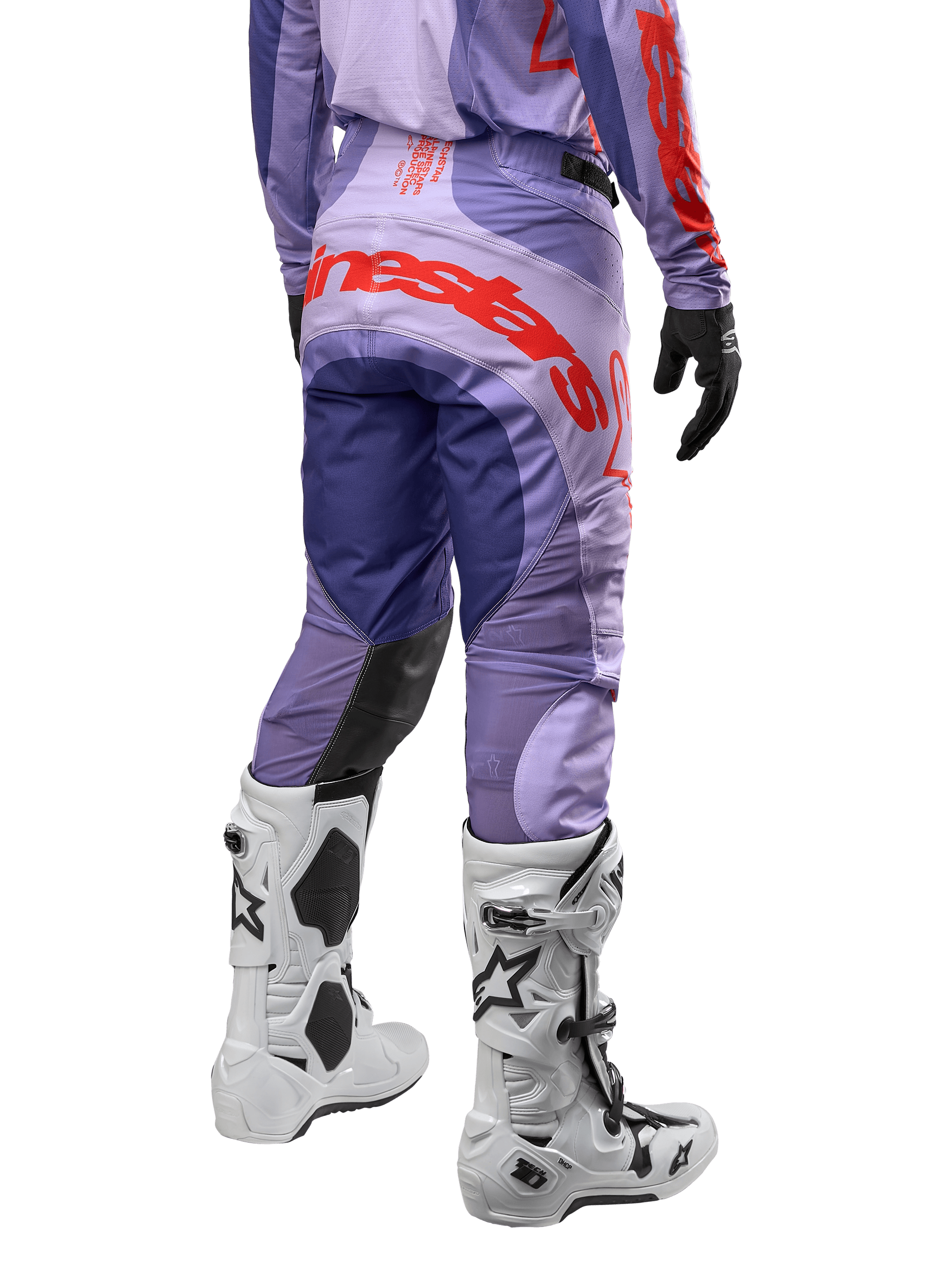 Alpinestars 2024 Techstar Ocuri crossbroek, motorcross broek, paars met feloranje accenten en grote logo-opdruk op het zitvlak, achteraanzicht, gedragen met witte motorcrosslaarzen en zwarte handschoenen