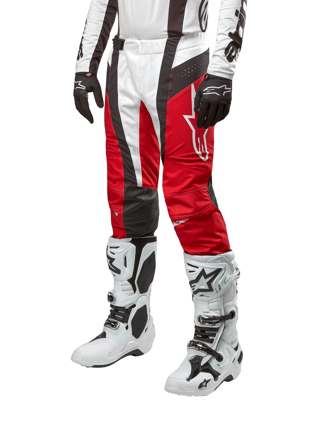 Alpinestars 2024 Techstar Ocuri crossbroek, motorcross broek, Mars rood, wit en zwart, gedragen met bijpassende wit-zwarte jersey, zwarte handschoenen en witte motorlaarzen met gespen, technische beschermende uitrusting op een witte achtergrond