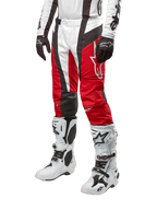 Alpinestars 2024 Techstar Ocuri crossbroek, motorcross broek, Mars rood, wit en zwart, gedragen met bijpassende wit-zwarte jersey, zwarte handschoenen en witte motorlaarzen met gespen, technische beschermende uitrusting op een witte achtergrond