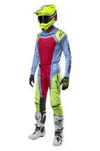 Alpinestars 2024 Techstar Ocuri crossbroek in lichtblauw, geel fluo en Red Berry, gecoördineerde race-uitrusting met bijpassende jersey, fluorgele helm en witte laarzen, vooraanzicht van een off-road competitie-outfit.