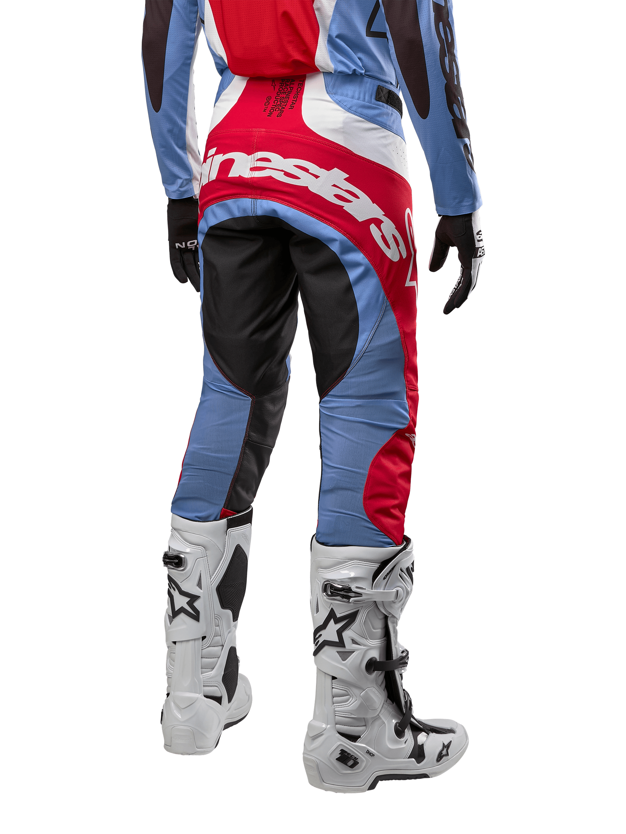 Alpinestars 2024 Techstar Ocuri broek, motorcrossbroek, lichtblauw, marsrood en wit, achteraanzicht met de nadruk op het grote rode Alpinestars-logo op het zitvlak, gedragen met witte motorcrosslaarzen en bijpassende jersey.