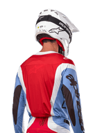 Alpinestars 2024 Techstar Ocuri Jersey, motorcross shirt, lichtblauw, Mars-rood en wit, achteraanzicht van rijder met bijpassende witte helm en zwarte crossbril, voorzien van opvallende zwarte branding op de mouwen en een ergonomische racepasvorm voor off-road prestaties