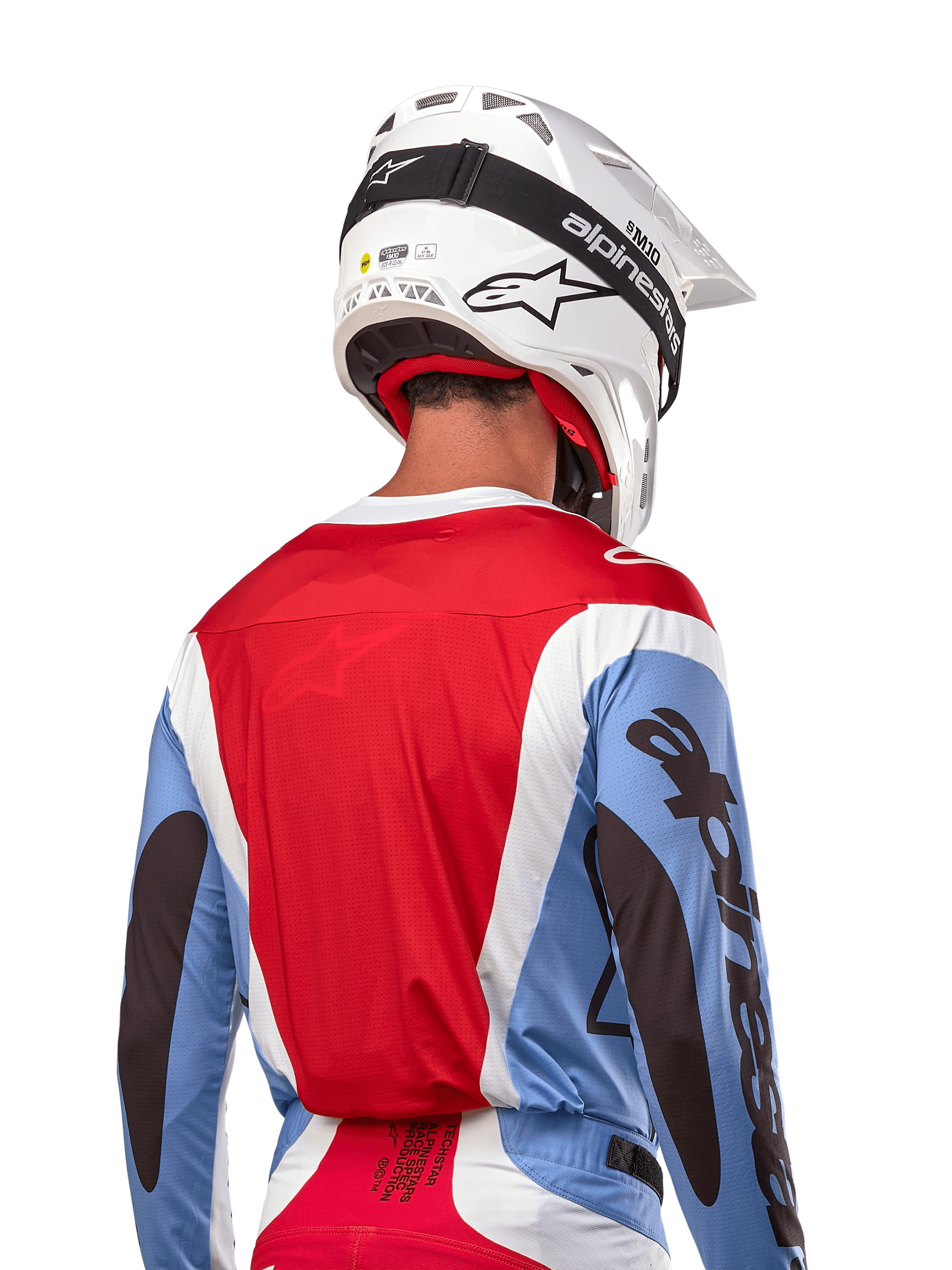 Alpinestars 2024 Techstar Ocuri Jersey, motorcross shirt, lichtblauw, Mars-rood en wit, achteraanzicht van rijder met bijpassende witte helm en zwarte crossbril, voorzien van opvallende zwarte branding op de mouwen en een ergonomische racepasvorm voor off-road prestaties