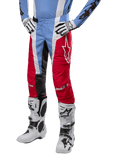 Alpinestars 2024 Techstar Ocuri broek, motorcross broek, lichtblauw, marsrood en wit, gedragen met lichtblauw shirt en witte laarzen, met het ster-logo op de dij en verstevigde knieën, complete off-road race-uitrusting