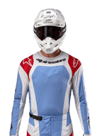 Alpinestars 2024 Techstar Ocuri Jersey, motorcross shirt, lichtblauw met rood en wit, vooraanzicht met laser-gesneden ventilatie en atletische pasvorm, gedragen met een witte helm en crossbril voor een professionele off-road racing look