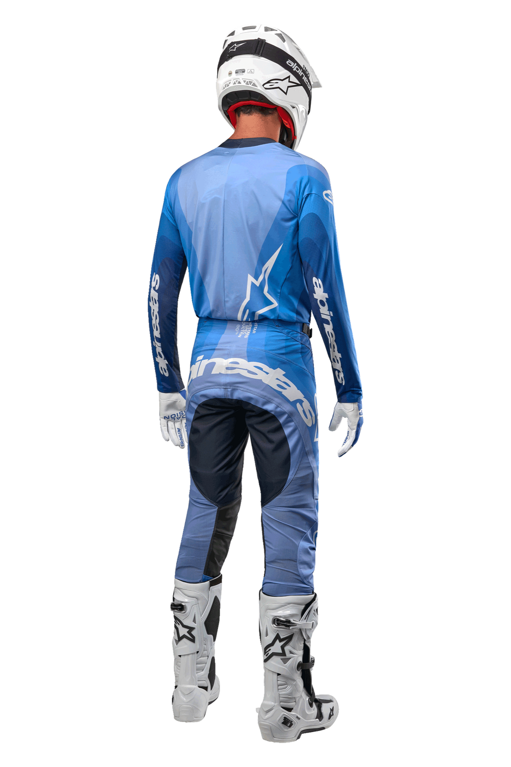 Alpinestars 2024 Techstar Pneuma broek, motorcrosser van achteren gezien in donkerblauw en lichtblauw, gecombineerd met bijpassende blauwe jersey, witte helm, handschoenen en laarzen, met opvallende Alpinestars-branding op het zitvlak en de mouwen.