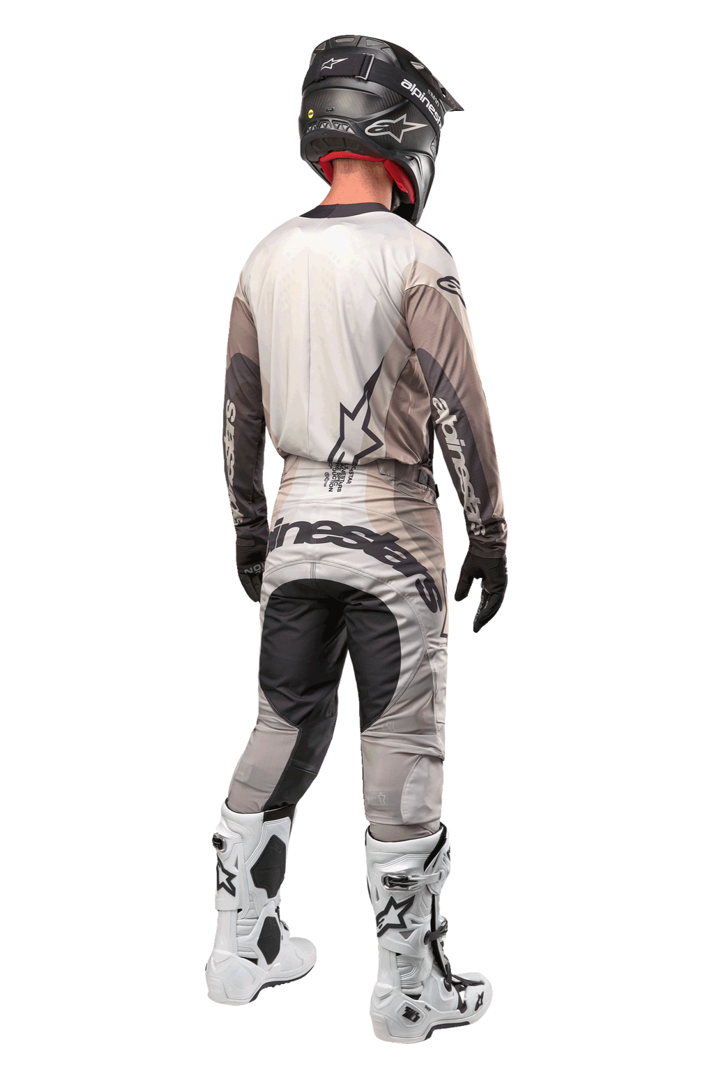 Alpinestars 2024 Techstar Pneuma broek, motocrossbroek, Dark Sand en Iron Dust Gray, achteraanzicht gedragen door een rijder met een bijpassende jersey, witte en zwarte laarzen en een zwarte helm, voorzien van opvallende Alpinestars-branding op het zitvlak en versterkte donkere panelen