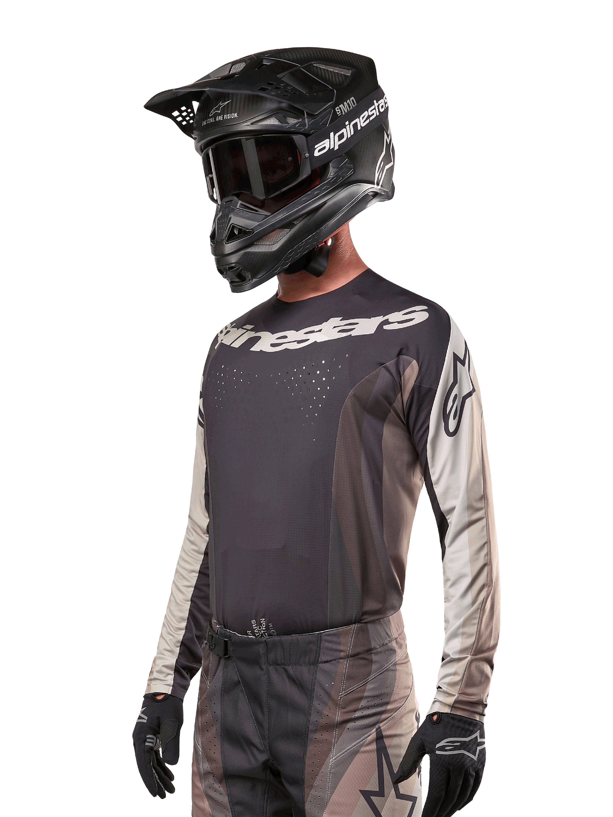 Alpinestars 2024 Techstar Pneuma Jersey, motorcross raceshirt, Dark Sand en Iron Dust grijs, performance top met lange mouwen met lasergesneden perforaties en witte logo's, gedragen met bijpassende broek en zwarte helm, atletische pasvorm voor off-road rijden.