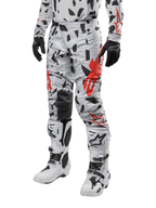 Alpinestars 2024 Techstar Rantera crossbroek, motorcross broek, Haze Gray Camo met zwart en rood abstract patroon, gedragen met bijpassende jersey, zwarte handschoenen en witte motorcrosslaarzen, ontworpen voor high-performance off-road racen