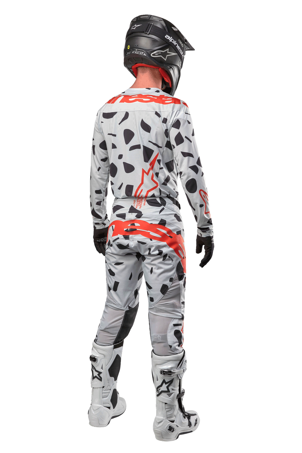 Motorcrosser van achteren in Alpinestars 2024 Techstar Rantera Pants, Haze Gray Camo met zwarte vlekken en rode logo's, bijpassende jersey, zwarte helm en witte laarzen, complete off-road race-outfit