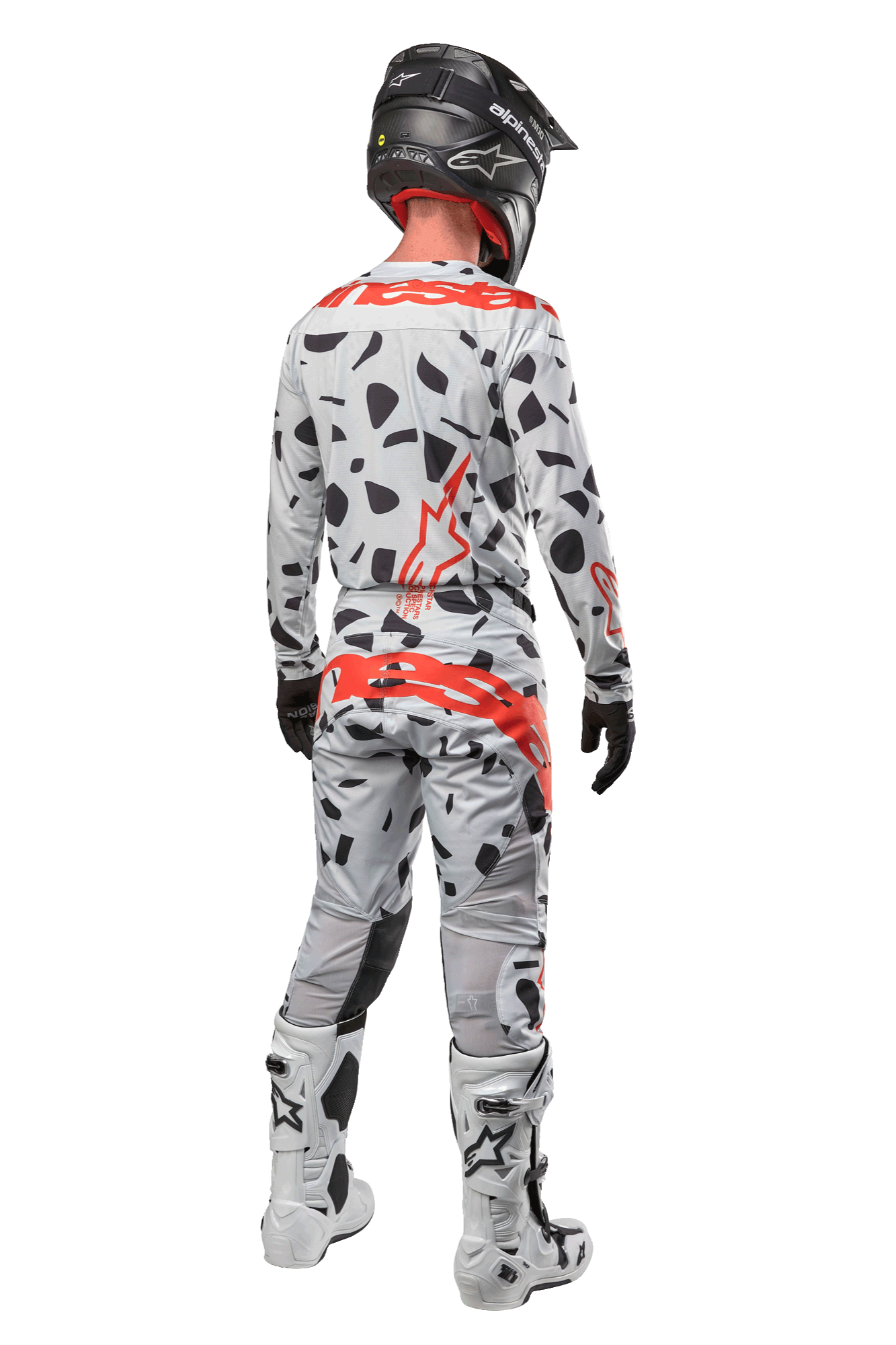 Motorcrosser van achteren in Alpinestars 2024 Techstar Rantera Pants, Haze Gray Camo met zwarte vlekken en rode logo's, bijpassende jersey, zwarte helm en witte laarzen, complete off-road race-outfit