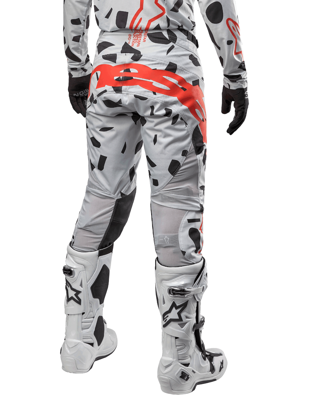 Alpinestars 2024 Techstar Rantera Pants, motorcross broek, Haze Gray Camo, met zwarte camouflagepatronen en een groot rood Alpinestars-logo op het zitvlak, achteraanzicht gedragen met witte laarzen en bijpassende race-uitrusting