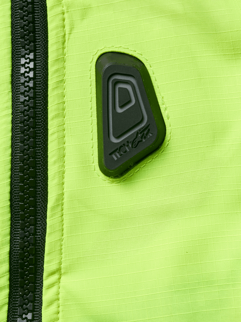 Alpinestars Tech-Air® 3 V2 Systeem, motor airbagvest, close-up van Yellow Fluo waterbestendige stof met zwarte rits, voorzien van een zwarte rubberen Tech-Air logopatch, high-visibility veiligheidsuitrusting