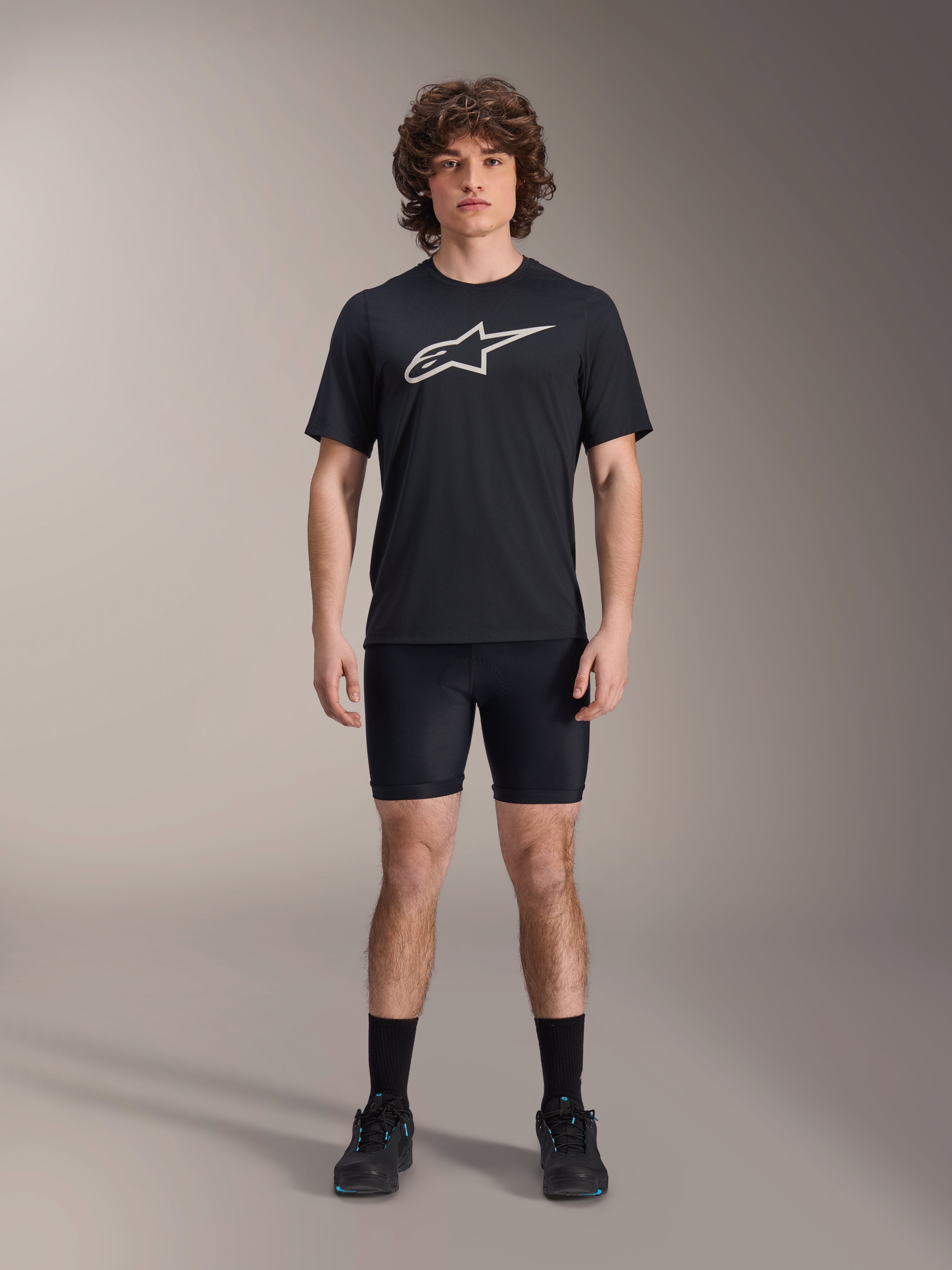 Alpinestars A-Dura Liner Shorts, zwarte fiets-binnenbroek, gedragen door een model met een zwart Alpinestars t-shirt met logo en zwarte fietsschoenen, nauwsluitend ontwerp voor MTB-prestaties en comfort in het zadel.