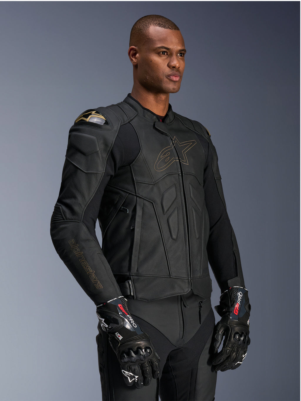 Alpinestars Dusk Leather Jacket, Black Laser motorjas, premium lederen constructie met goudkleurige Alpinestars logo-omtrek en branding op de mouwen, externe DFS schouderbescherming, gecombineerd met GP Pro handschoenen, hoogwaardige race-uitrusting