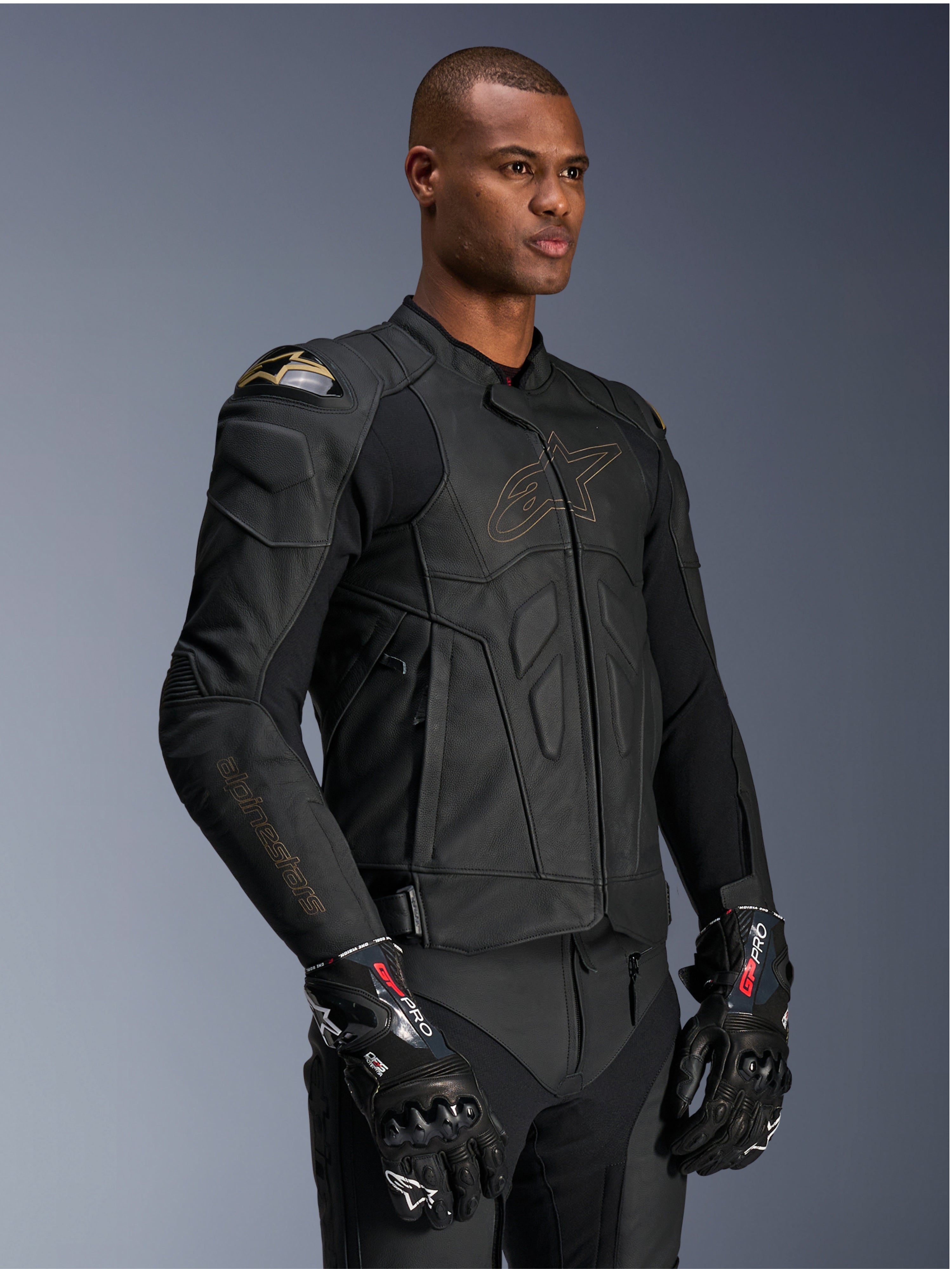 Alpinestars Dusk Leather Jacket, Black Laser motorjas, premium lederen constructie met goudkleurige Alpinestars logo-omtrek en branding op de mouwen, externe DFS schouderbescherming, gecombineerd met GP Pro handschoenen, hoogwaardige race-uitrusting