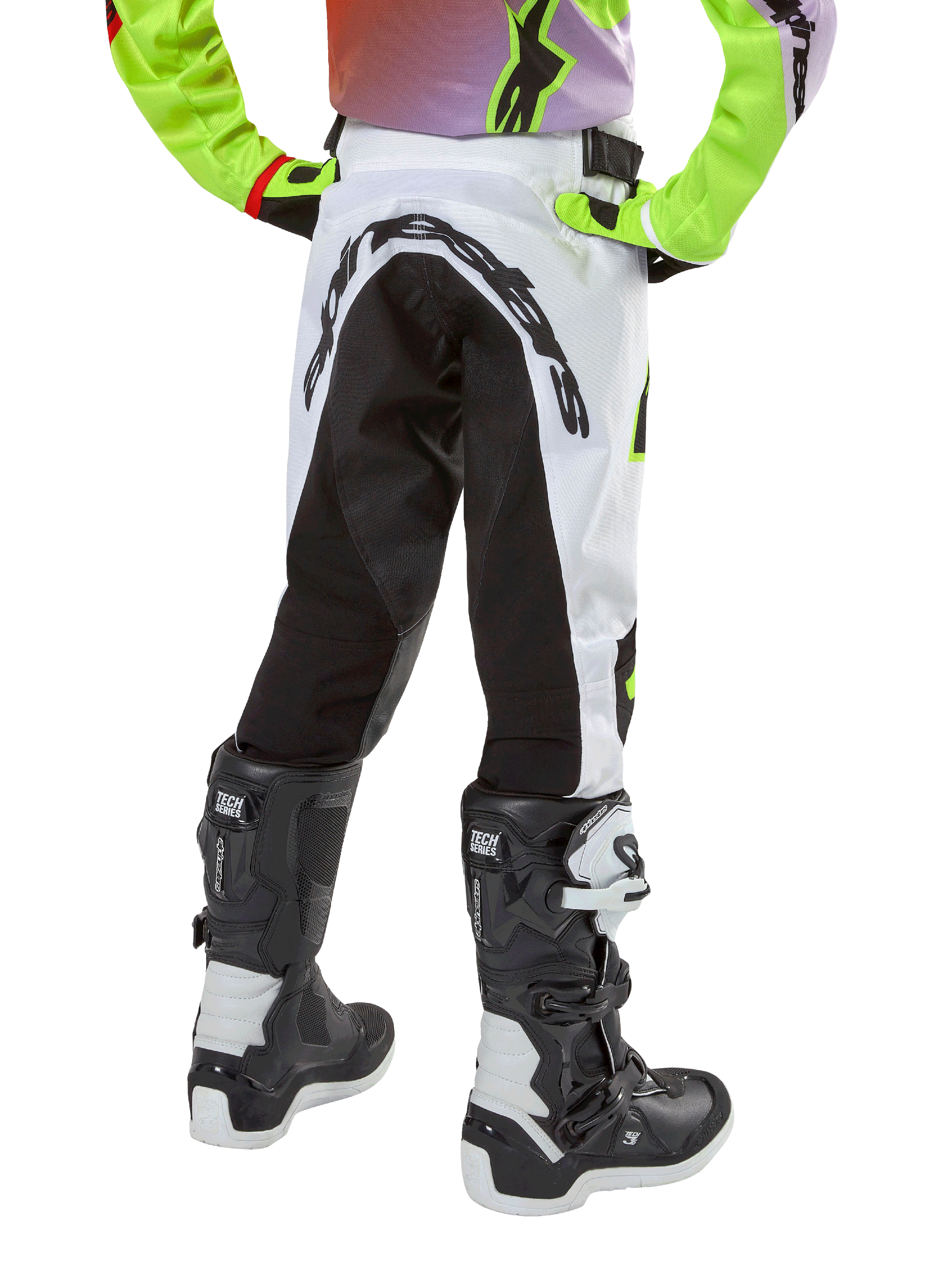 Alpinestars 2024 Youth Racer Lucent broek, motorcross broek, wit en zwart met neon accenten, achteraanzicht toont groot stretchpaneel aan de achterkant en Alpinestars-logo, gedragen met zwart-witte Alpinestars Tech Series laarzen