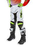 Alpinestars Youth 2024 Racer Lucent motorcrossbroek, crossbroek, wit, neonrood en geel fluo, weergave van het onderlichaam met zwarte stretchpanelen en neonaccenten, gedragen met zwart-witte racelaarzen en neongele handschoenen, technische off-road uitrusting voor de jeugd