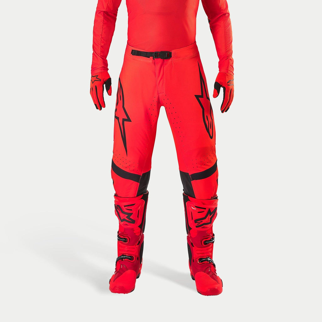 Alpinestars Supertech Ember LE Pants, Motocross Pants, Red Fluo and Bright Red with Black accents, featuring bold black star logos on the thighs, black waist buckle and knee panels, worn with matching red boots and gloves for a coordinated racing outfit.